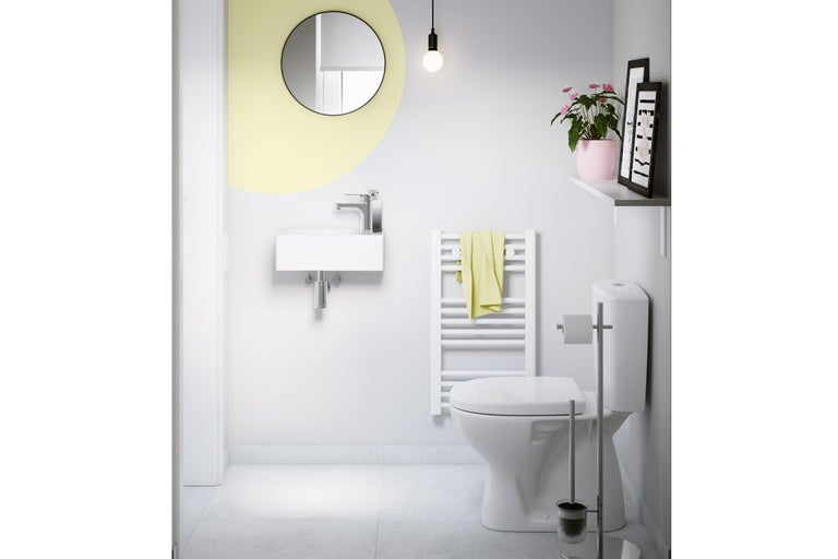 WC visiteurs moderne et lumineux avec petit lavabo mural, miroir rond, radiateur sèche-serviettes blanc et WC au sol.