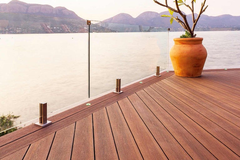 Terrasse avec garde-corps en verre et plancher en bois avec vue sur le paysage marin