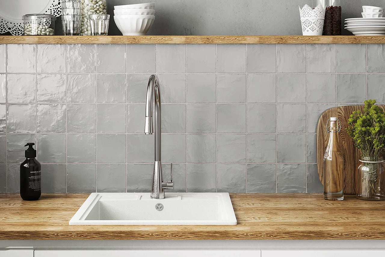 Küchenspüle mit Armatur vor grauen Fliesen