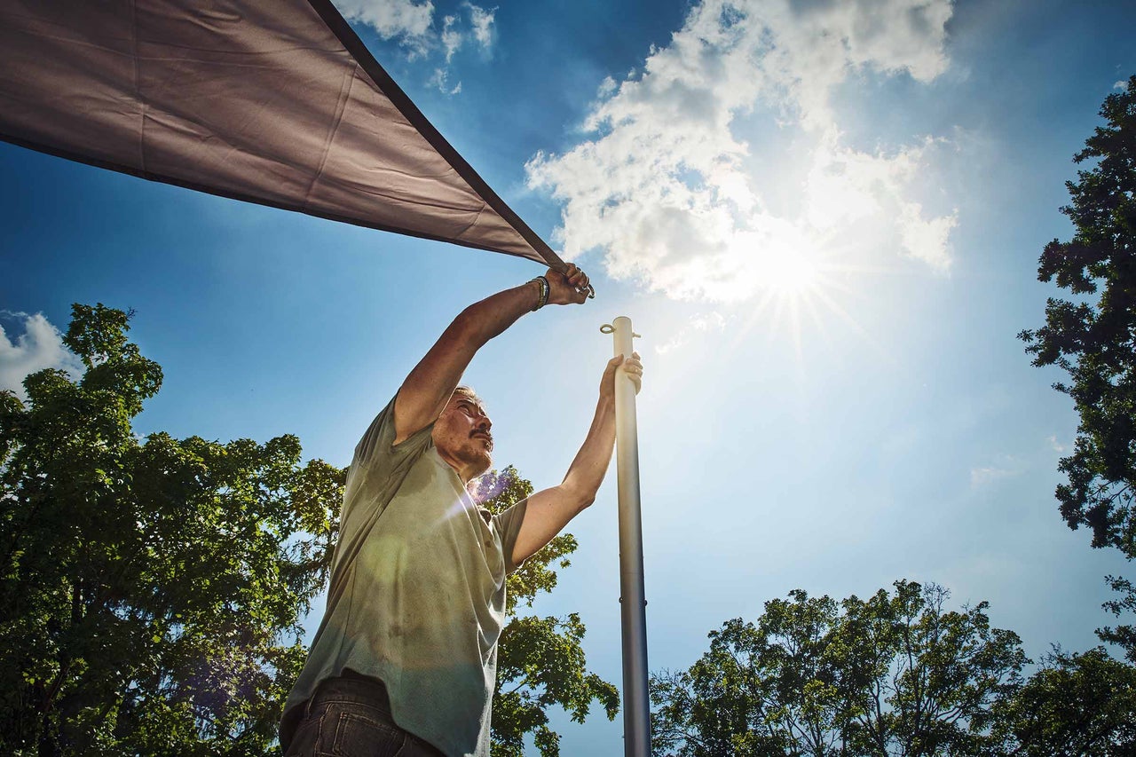 Frau befestigt Sichtschutzplane mit Haken auf Balkon