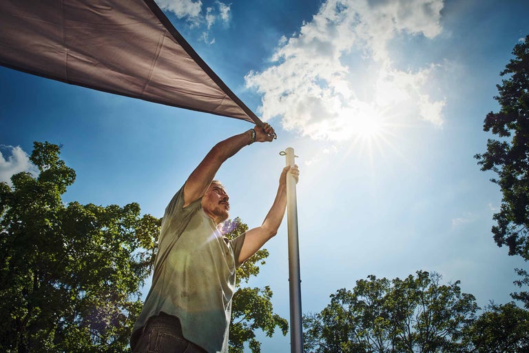 Frau befestigt Sichtschutzplane mit Haken auf Balkon