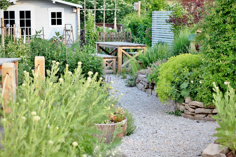 Aménagement de jardin avec cabanon, table en bois et allée de gravier