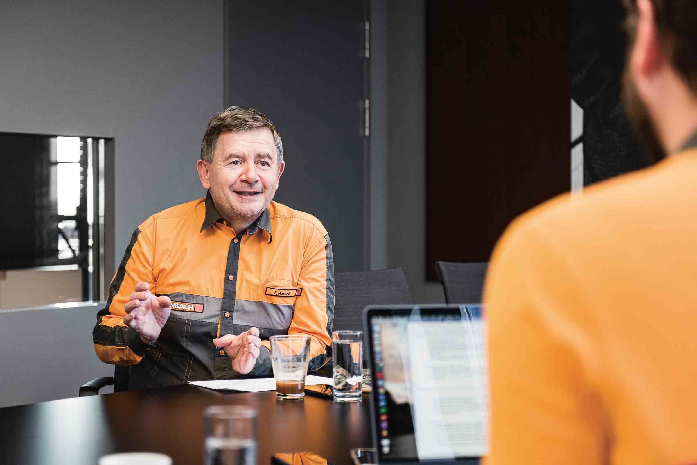Scène de réunion avec une personne portant une chemise Hornbach orange
