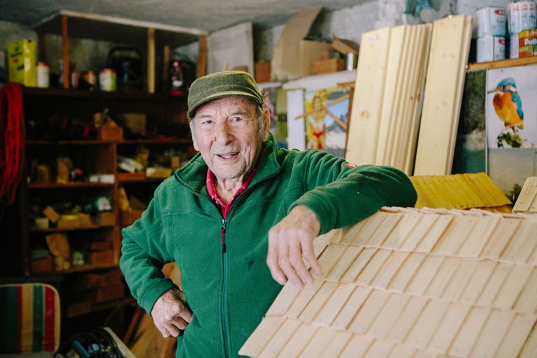 Un homme s'appuie sur un projet de toit en bardeaux de bois dans un atelier.