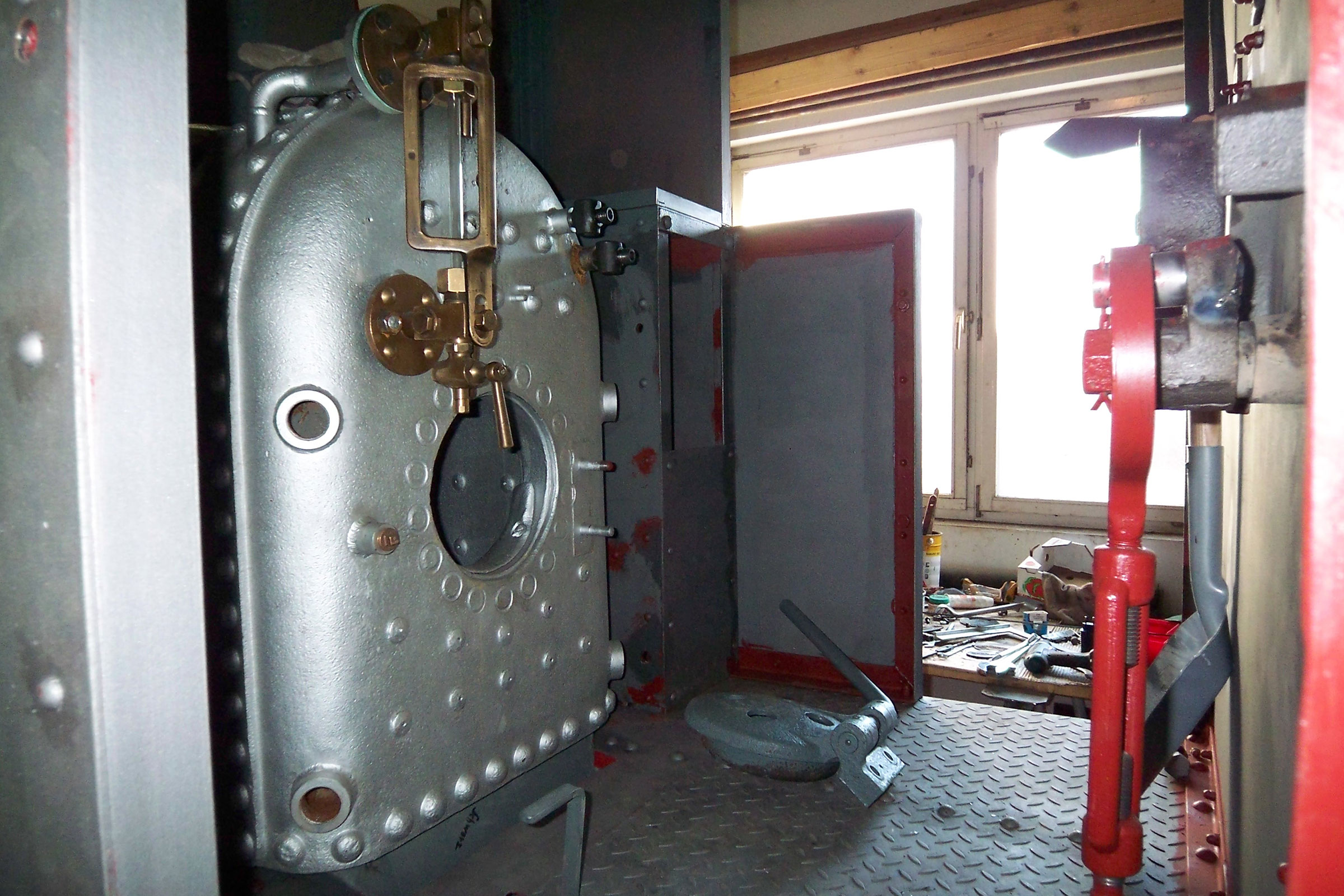 Vue intérieure d'une chaufferie avec chaudière et outils.
