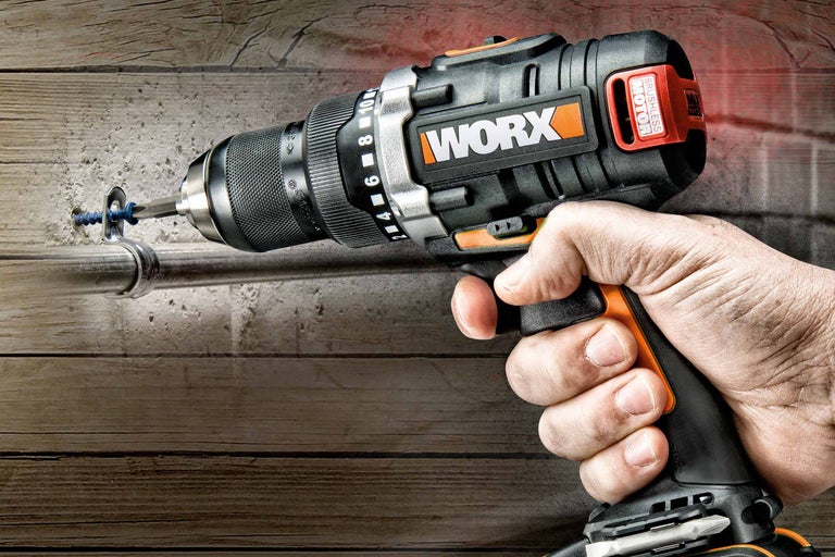 Une main tient une perceuse-visseuse sans fil Worx qui visse une vis dans un mur.