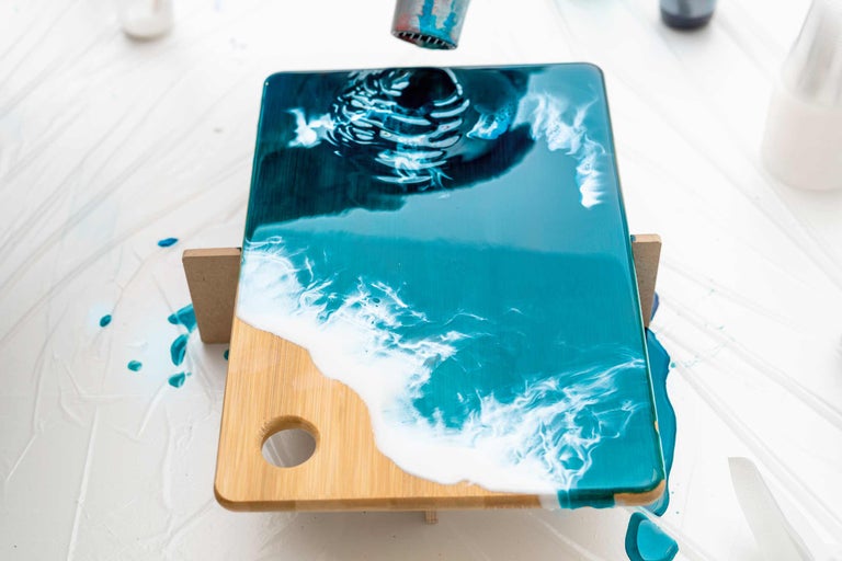 Planche à découper en bambou avec motif océanique en cours de traitement avec un pistolet à air chaud