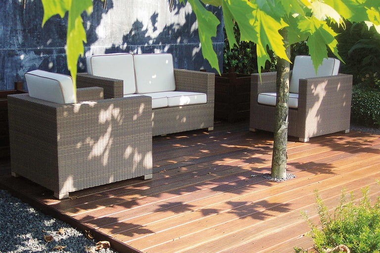 Salon de jardin en polyrotin avec coussins clairs sur terrasse en bois