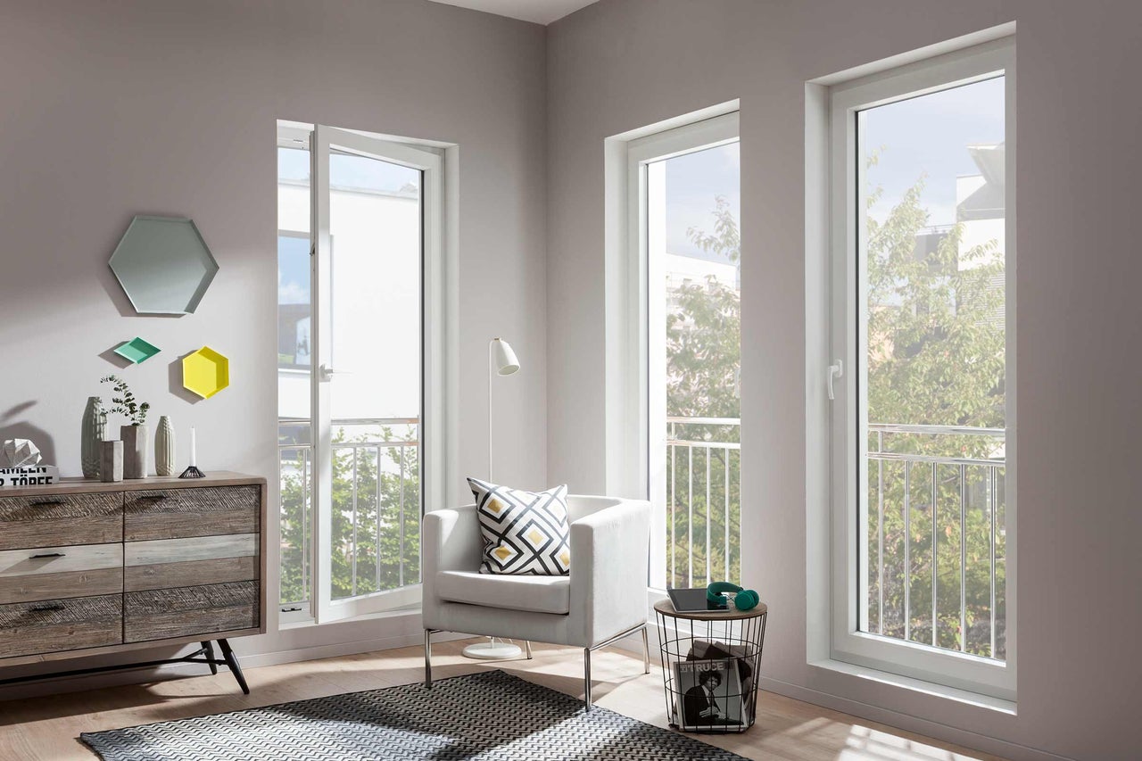 Séjour lumineux avec fenêtres en plastique blanc, fauteuil et commode