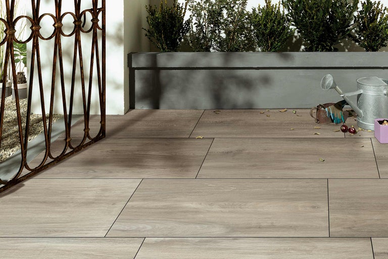 Terrasse avec carrelage imitation bois, clôture en fer et plantations