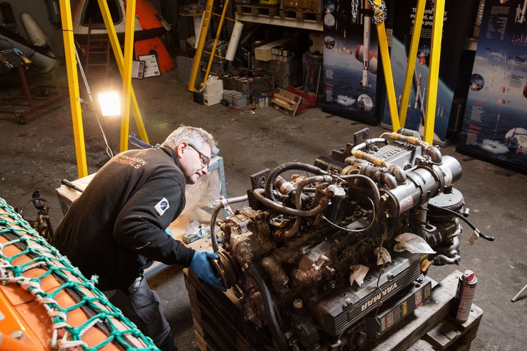 Un homme travaille sur un moteur Yanmar dans un atelier