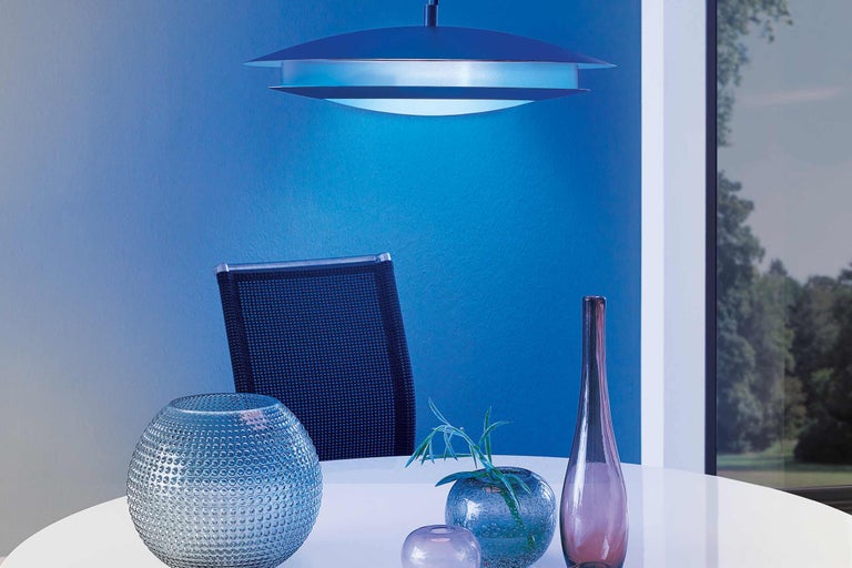 Scène avec une suspension, une chaise et différents vases sur une table.