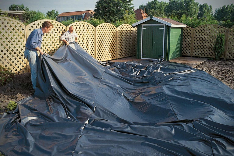 Zwei Männer verlegen Teichfolie im Garten für die Teichgestaltung