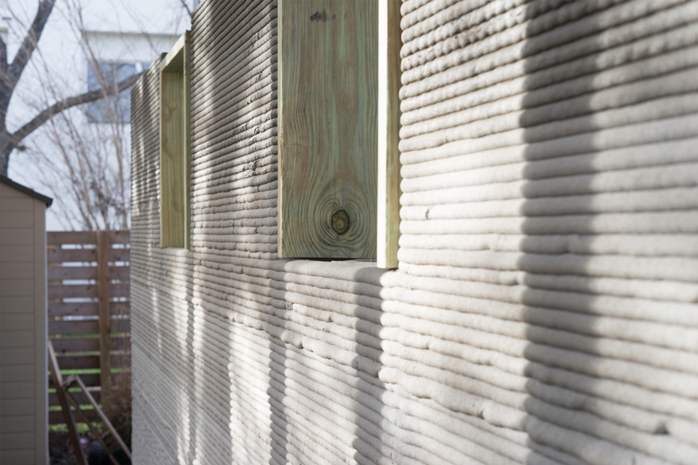 Gros plan d'un mur de maison en béton imprimé en 3D avec des cadres en bois pour les ouvertures de fenêtres
