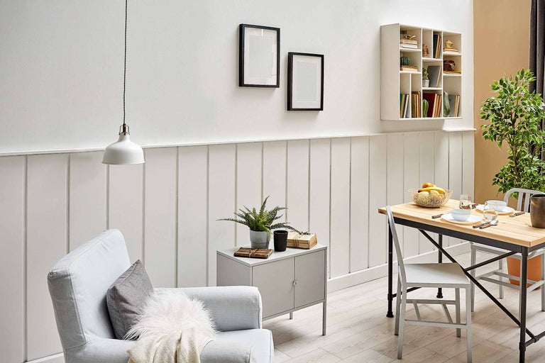 Salon lumineux avec fauteuil, table, décoration et étagère murale