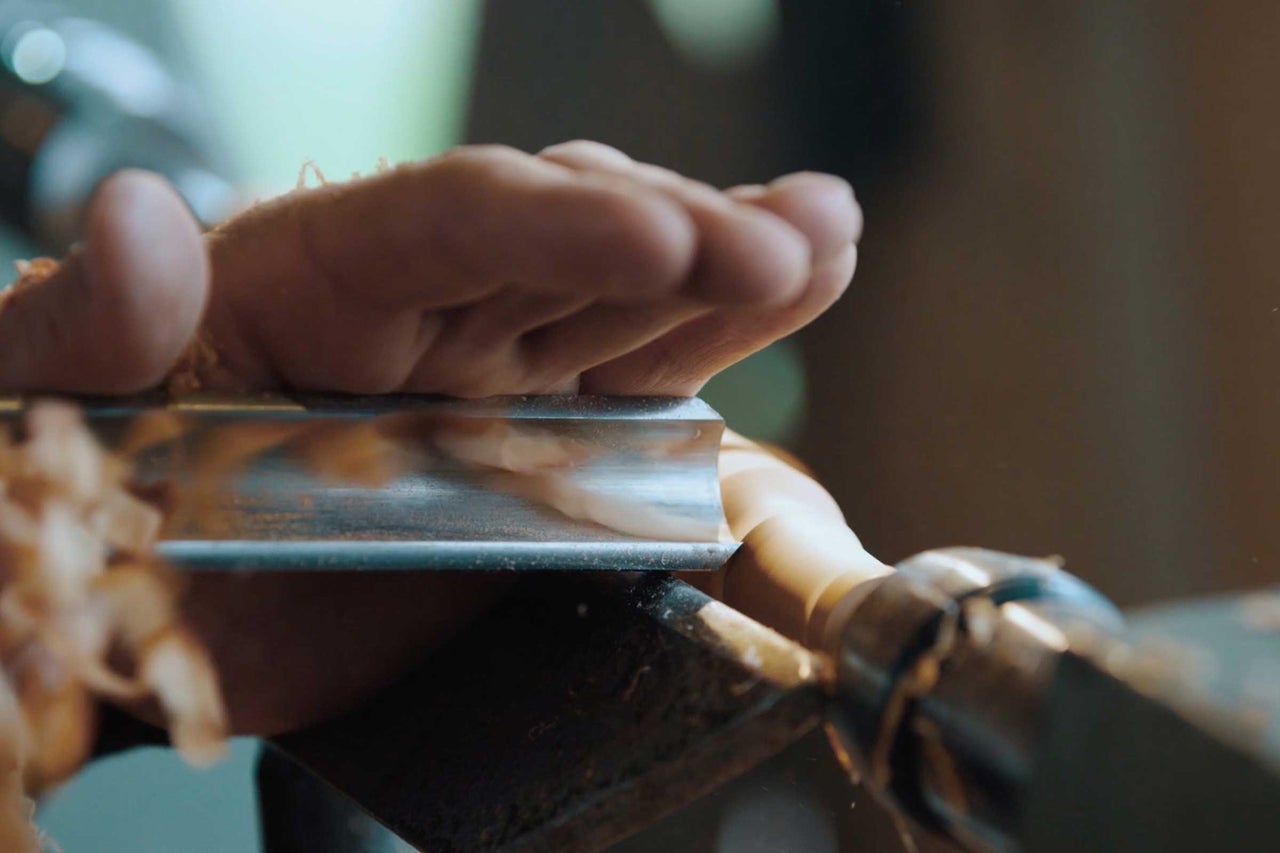 Gros plan d'une main tenant un outil de tournage lors du tournage d'une pièce de bois.