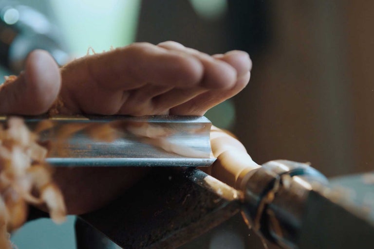Gros plan d'une main tenant un outil de tournage lors du tournage d'une pièce de bois.