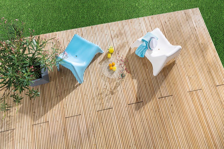 Vue de dessus d'une terrasse en bois avec deux chaises, une table d'appoint et un pot de plantes à fleurs.