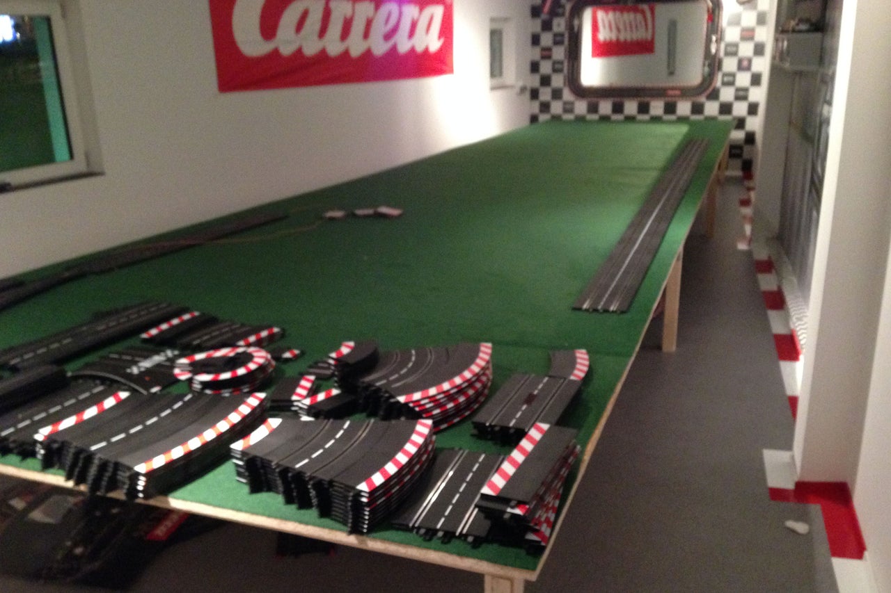 Circuit de course avec des éléments de rail et le logo Carrera sur le mur