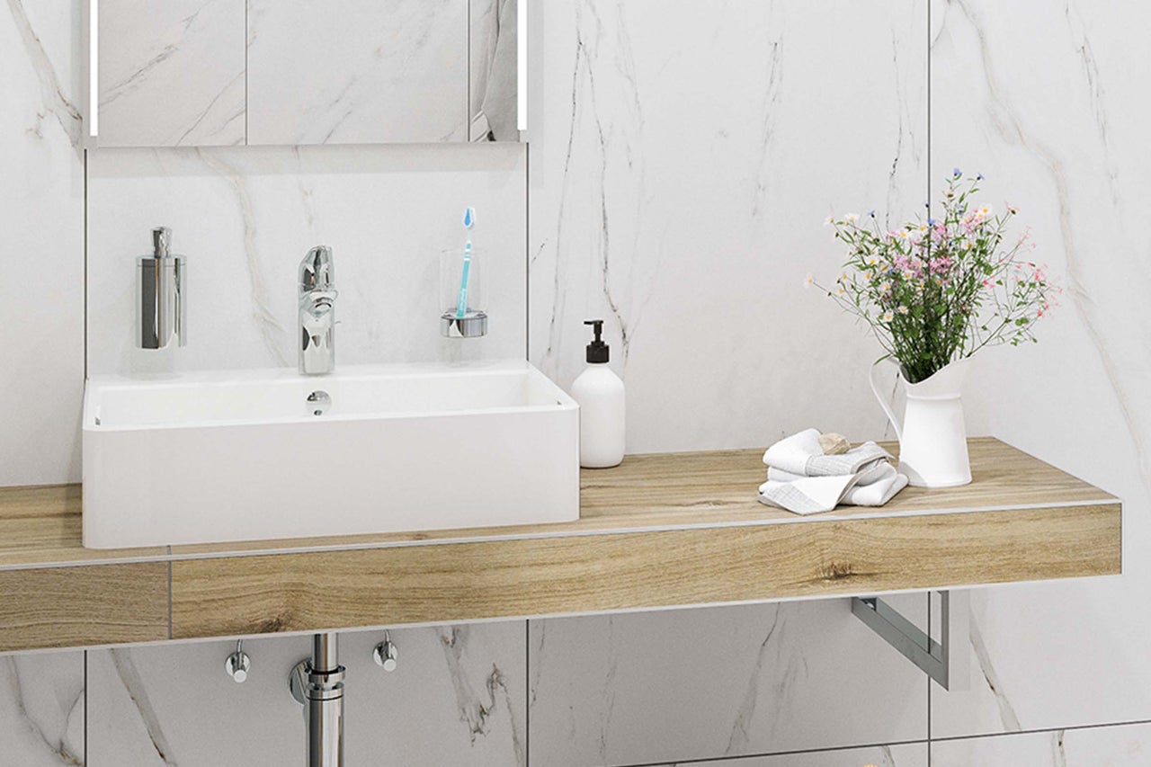 Helles Badezimmer mit Waschbecken, Armatur, Handtüchern und Blumenvase auf einem Holztisch