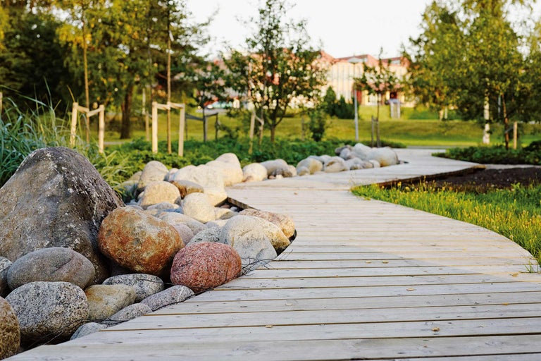 Allée en bois dans le jardin avec des pierres et des espaces verts