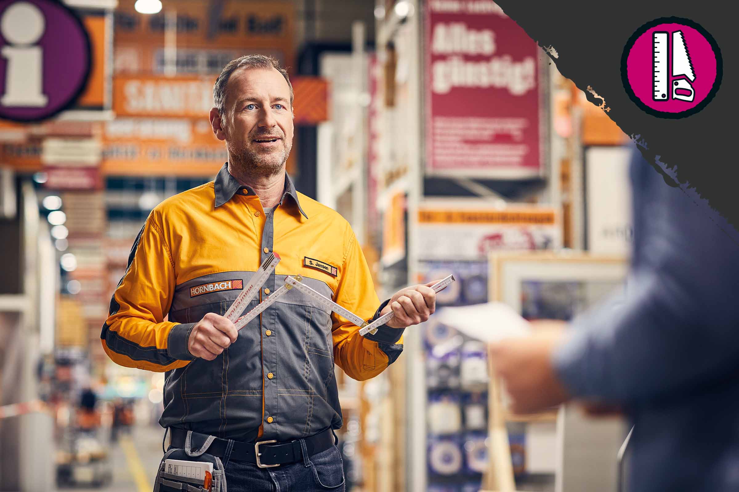 Ein Hornbach Mitarbeiter hält einen Gliedermaßstab in einem Hornbach Markt.