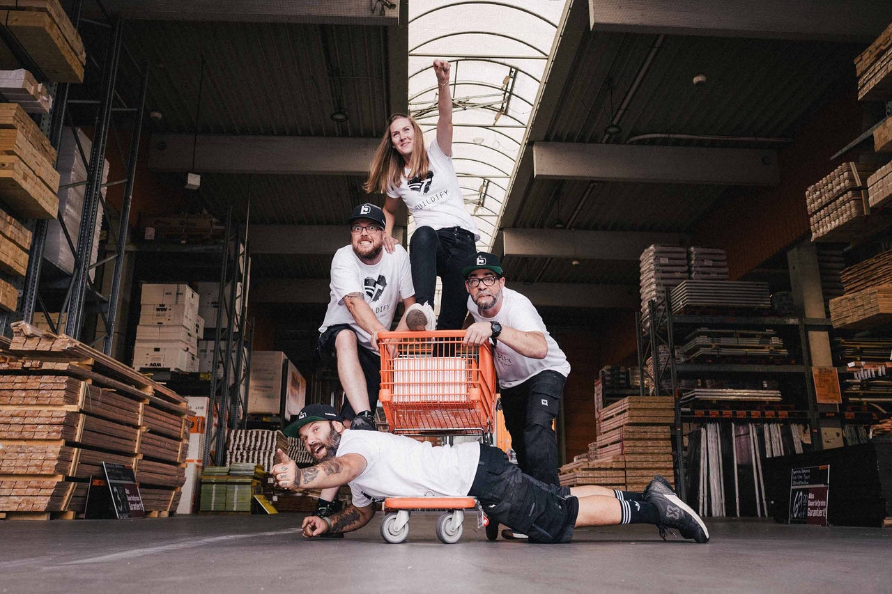 Groupe de personnes dans le magasin de bricolage Hornbach avec un chariot et du bois de construction en arrière-plan.