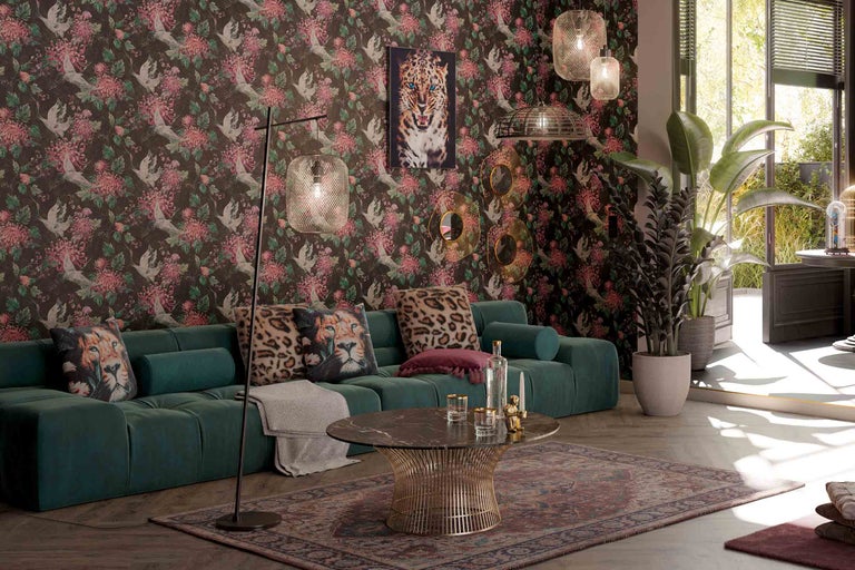 Wohnzimmer mit grüner Couch, gemusterter Tapete und dekorativen Elementen wie Kissen und Lampen