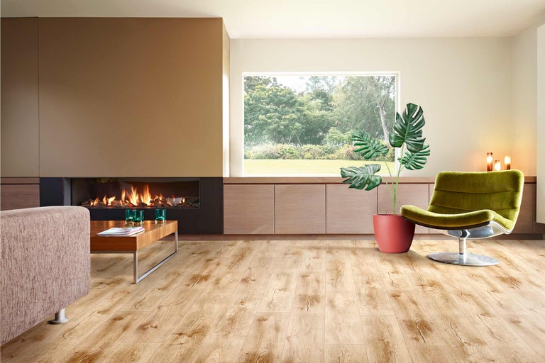 Heller Wohnraum mit Kamin, Holzfussboden, Sessel und Zimmerpflanze.