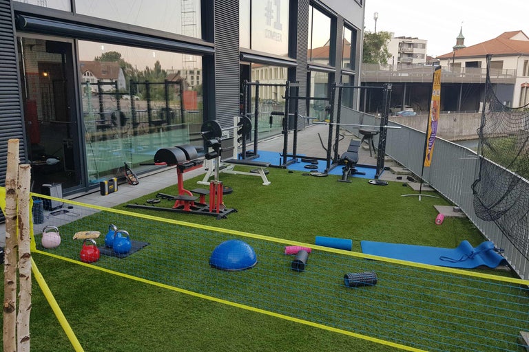 Aussenbereich eines Fitnessstudios mit Fitnessgeräten und -zubehör auf Kunstrasen
