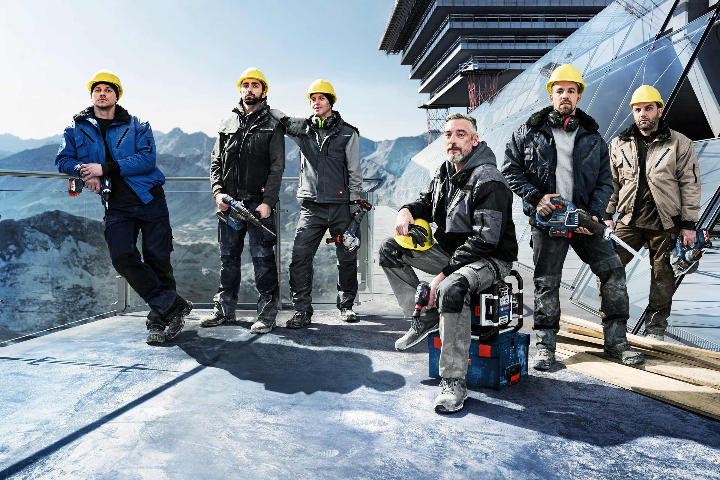 Groupe d'ouvriers du bâtiment avec outils et vêtements de protection devant un projet de construction