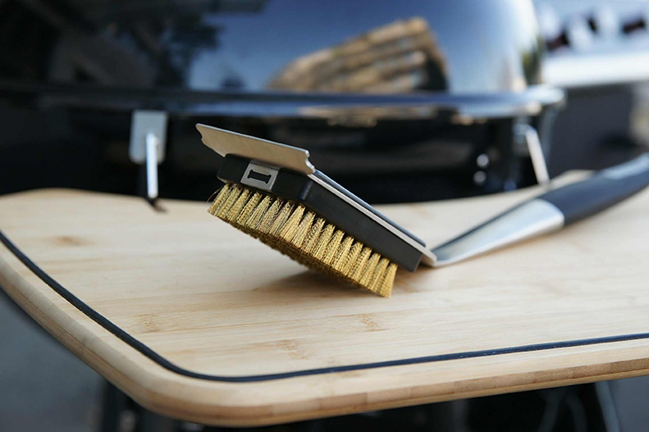 Grillbürste mit Schaber auf einem Holztisch