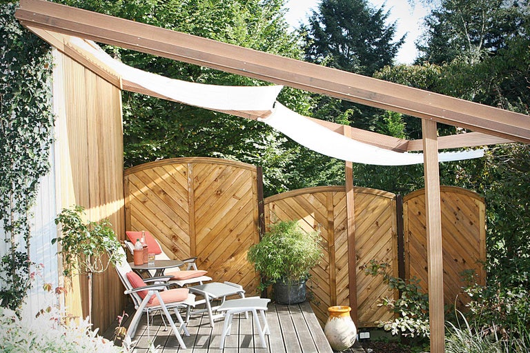 Coin salon dans le jardin avec terrasse en bois, brise-vue et voile d'ombrage