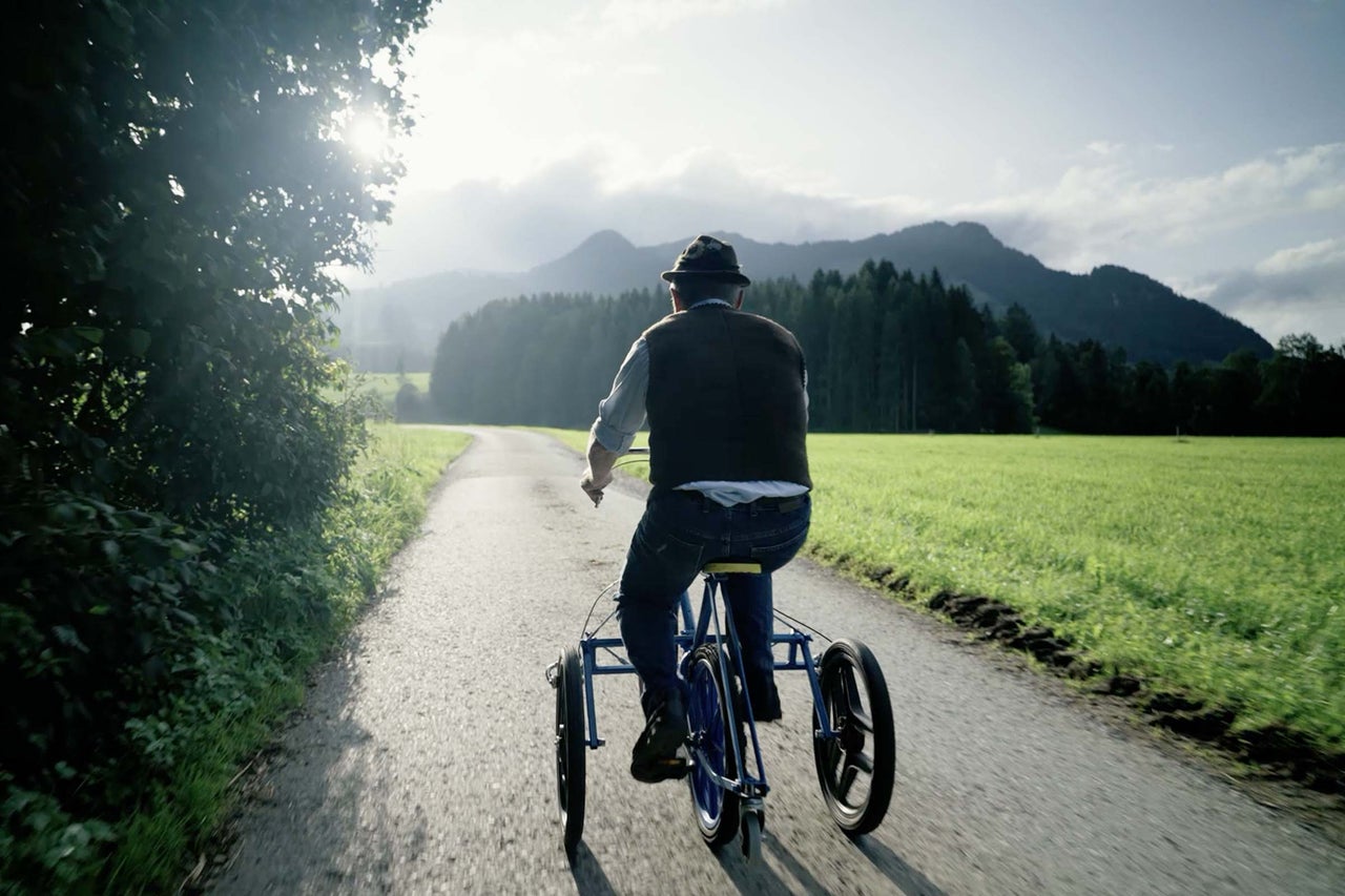 Homme conduisant un tricycle sur une route de campagne