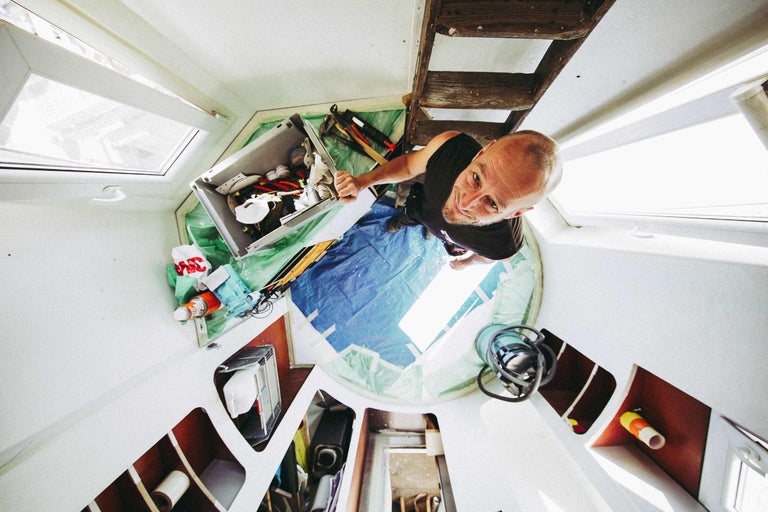 Homme avec une boîte à outils et une échelle dans une pièce avec une fenêtre de toit pour des travaux de rénovation