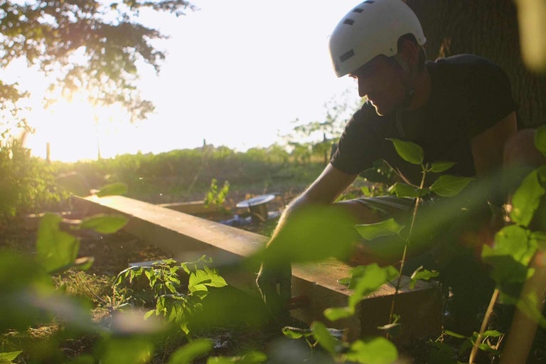 Ein Mann mit Helm arbeitet an einem Holzprojekt im Garten.