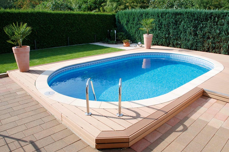 Piscine avec terrasse en bois et échelle dans un jardin.