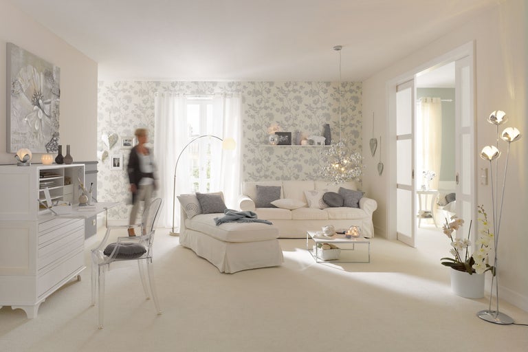 Helles Wohnzimmer mit Sofa, Sessel, Schreibtisch und dekorativer Blumenvliestapete