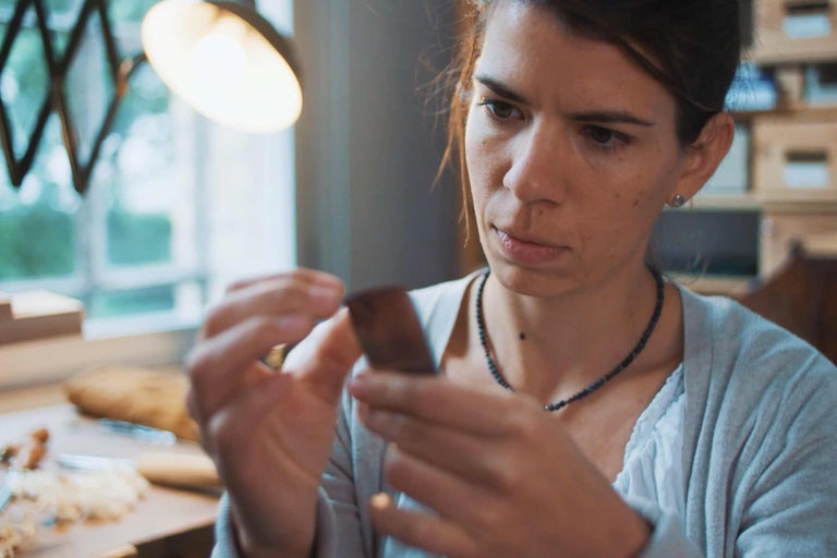 Femme examinant un morceau de bois dans un atelier