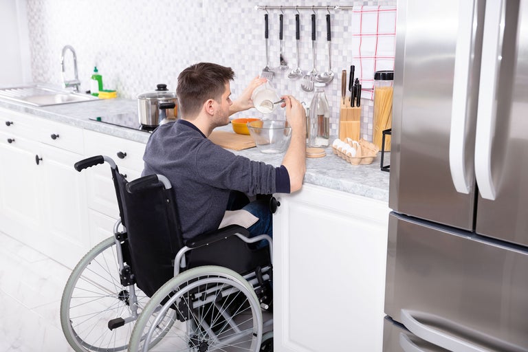 Un homme en fauteuil roulant prépare des plats dans une cuisine accessible