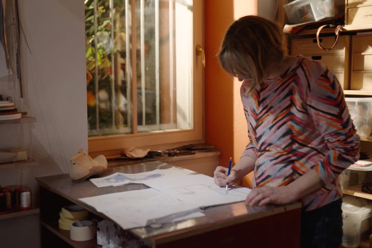 Une femme dessine un projet sur papier dans un atelier.
