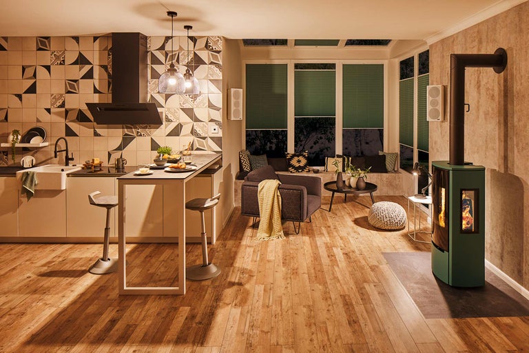 Pièce à vivre avec cuisine, coin salon près de la fenêtre, fauteuil et poêle à bois