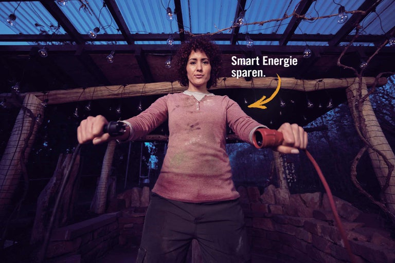 Une femme tient une rallonge sous un éclairage extérieur.