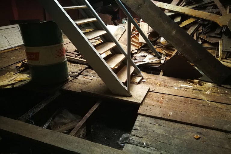 Grenier avec escalier, restes de bois et fût d'huile