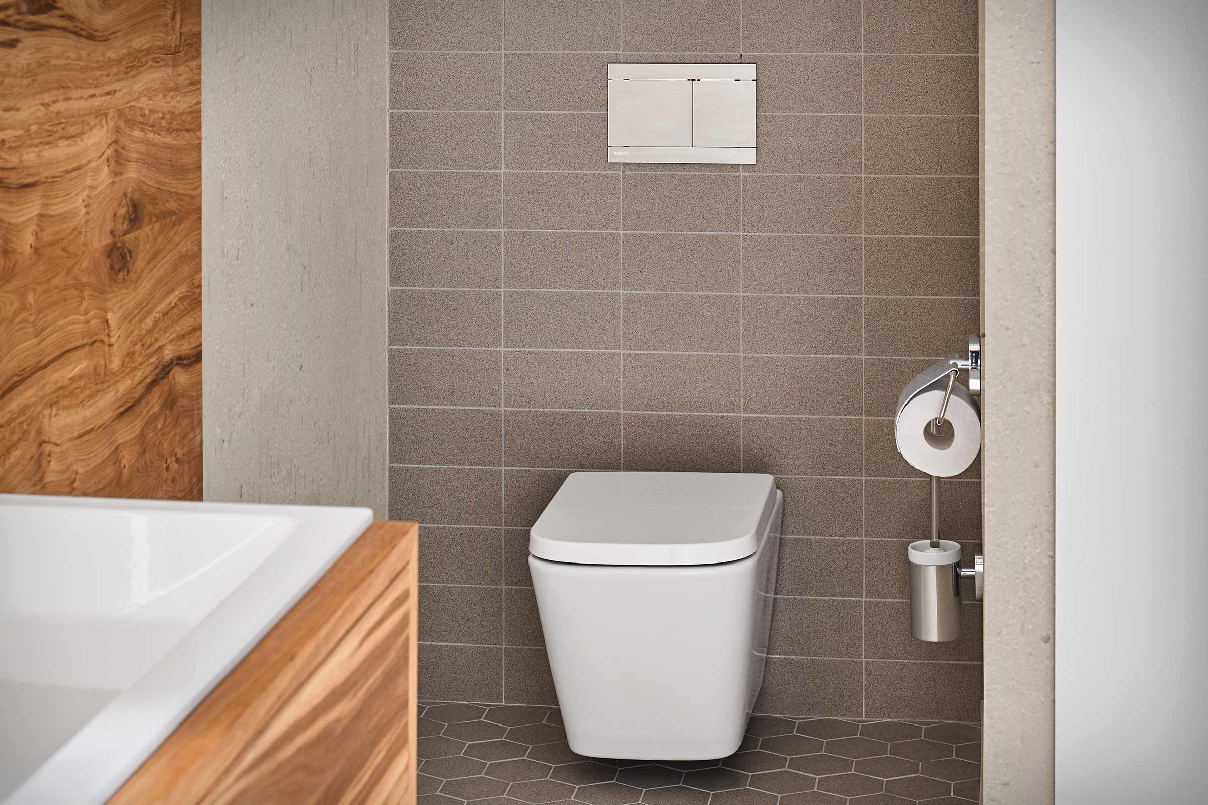 Salle de bains moderne avec WC suspendu, plaque de commande et porte-papier toilette