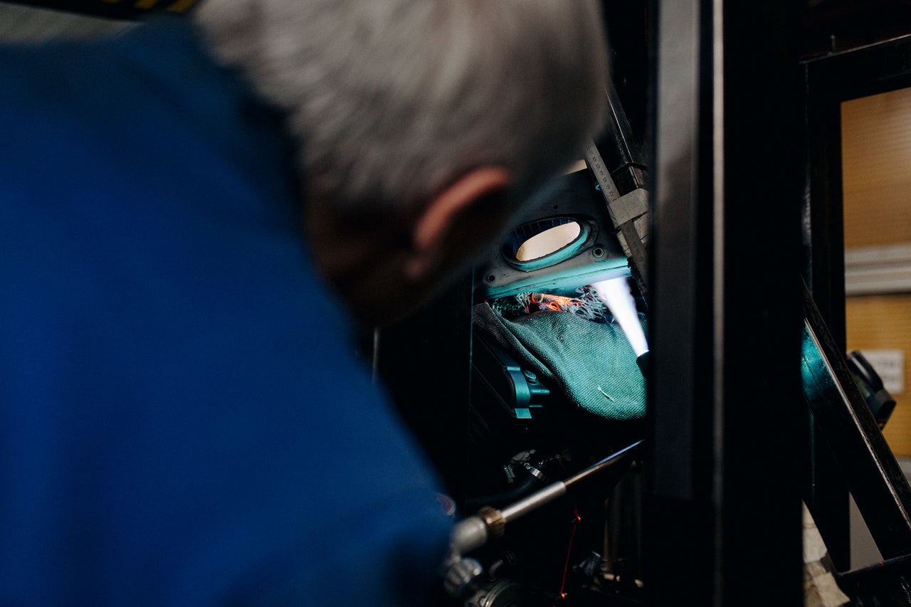 Mechaniker arbeitet an einer Maschine mit Werkzeugen und einer Decke