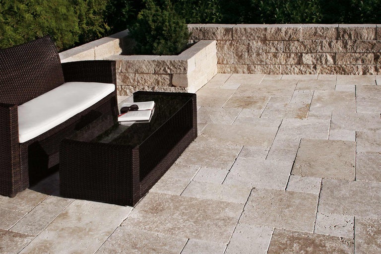 Terrasse avec salon de jardin en rotin, table et pavés en travertin