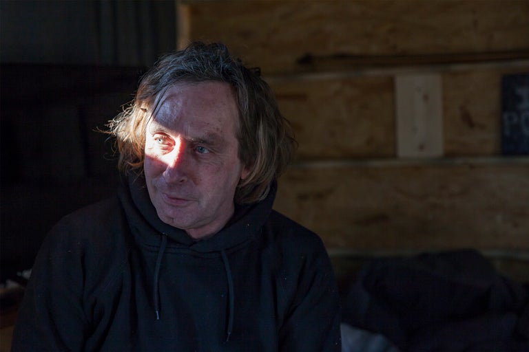 Portrait d'un homme avec un sweat à capuche devant un mur en bois