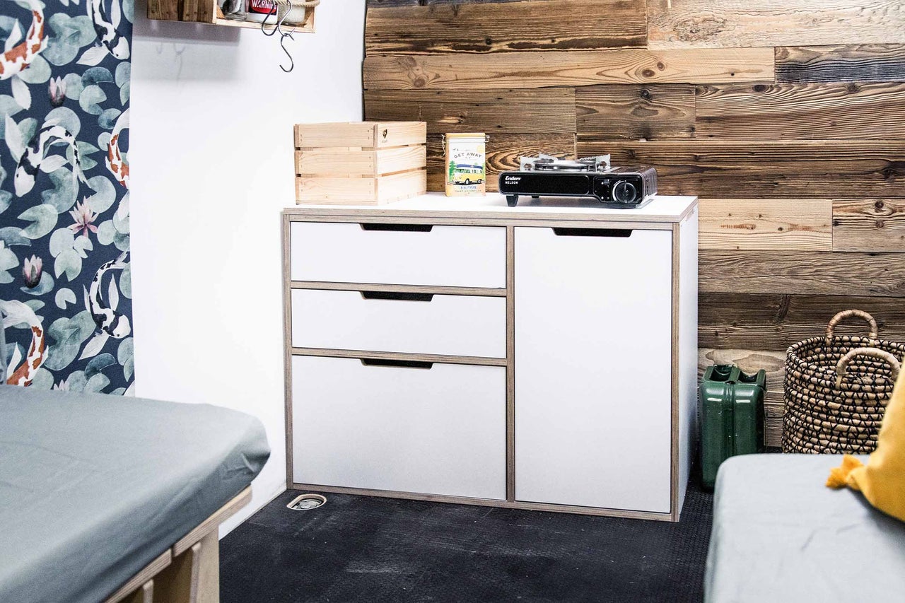 Intérieur avec commode, réchaud de camping et caisses en bois