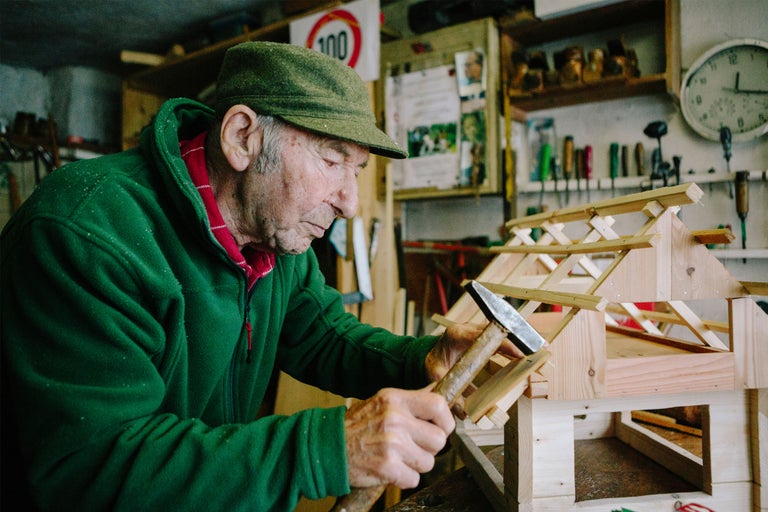 Un homme assemble une maison en bois dans un atelier à l'aide d'un marteau.